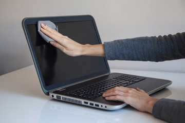 Young woman cleanig laptop screen with soft tissue