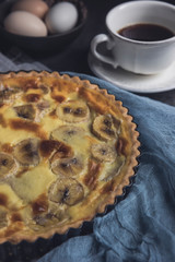 Banana custard tart with cup of coffee. Vertical