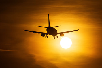 Silhouette of an air plane near to the sun with beautiful red clouds in background