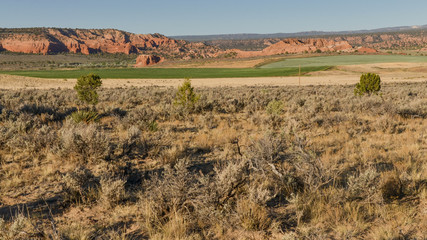 green farming fields between red sandstone canyons in Cannonville, Kane county, Utah