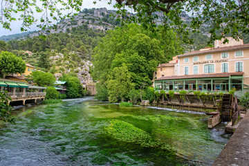 Fototapeta na wymiar River landscape. On the banks of the Sorgue and in the village are numerous restaurants, cafes and shops, Fontaine de Vaucluse, Provence, Luberon, Vaucluse, France