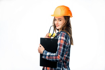 Portrait of beautiful worker model with hard hat and yellow glasses touching her lips isolated on white background. Female builder in helmet holding black folder