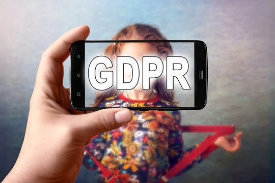 GDPR - the child is photographed from a smartphone, the image on the screen is hidden behind the inscription  General Data Protection Regulation.