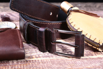 Watch, leather belt and wallet, bottle with cologne on wooden background. Stylish mens business accessories.