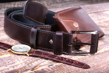 Watch, leather belt and wallet, bottle with cologne on wooden background. Stylish mens business accessories.