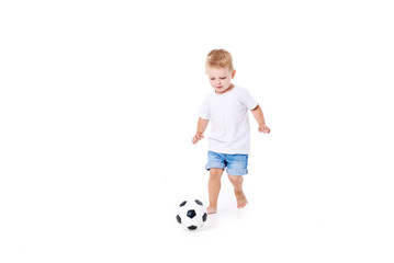 Little cute kid baby boy 3 years old, football fan in white t-shirt playing with soccer ball...
