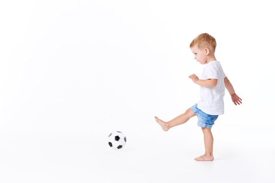 Little cute kid baby boy 3 years old, football fan in white t-shirt playing with soccer ball isolated on white background.  lifestyle concept. Copy space for text