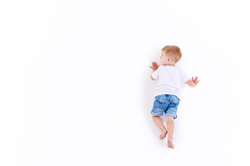 Little caucasian boy in white clothes on white wall, white background isolated. View from the back 