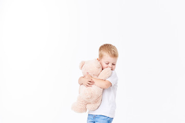 Cute boy plaing with toy fur bear on floor, isolated on white background