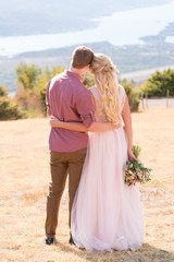 newlyweds stand in a meadow hugging each other