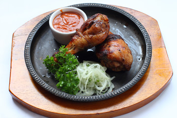 Grilled chicken grill with a cup of sauce, parsley and onion in a metal tray