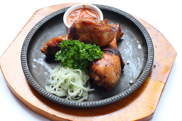 Grilled chicken grill with a cup of sauce, parsley and onion in a metal tray