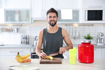 Young man preparing protein shake at table in kitchen