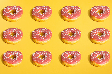 Flat lay of donuts and shadows pattern on yellow background. Top view