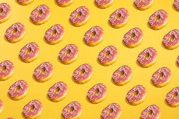 Flat lay of donuts and shadows pattern on yellow background. Top view
