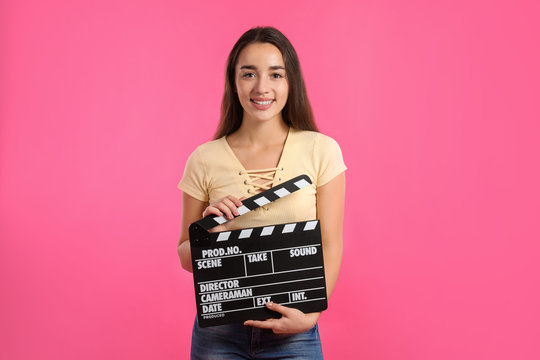 Woman with clapperboard on color background. Cinema show