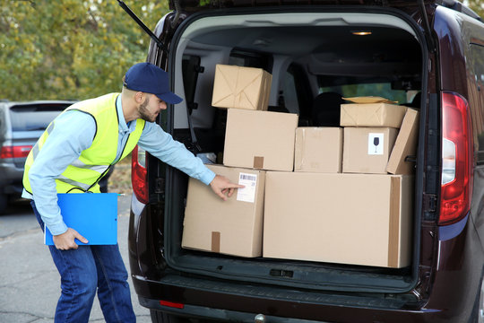 Young courier checking amount of parcels in delivery van, outdoors