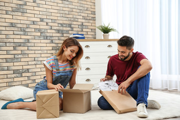 Young couple opening parcels on floor at home