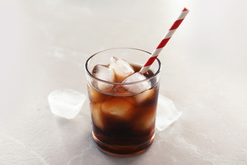 Glass of refreshing cola with ice on grey background