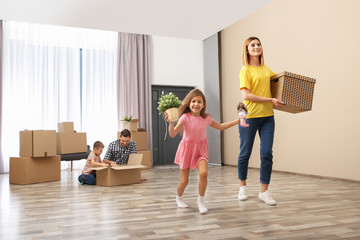 Happy family unpacking their belongings near pile of moving boxes indoors