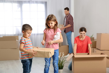 Fototapeta na wymiar Happy family unpacking boxes in their new house. Moving day