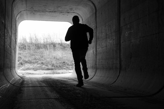 man running through dark tunnel escaping