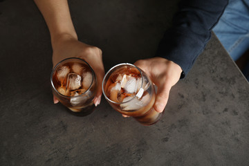 Friends with glasses of tasty refreshing cola at grey table, top view