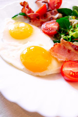 English breakfast. Omelet with tomatoes, bacon and salad on a white plate
