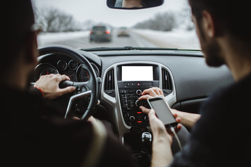 The man holds the phone in his hand. In the car
