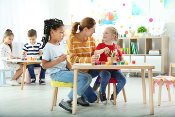 Obraz premium Children with female teacher at painting lesson indoors
