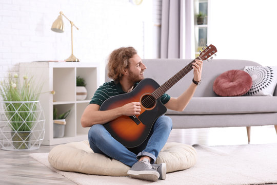 Young man playing acoustic guitar in living room
