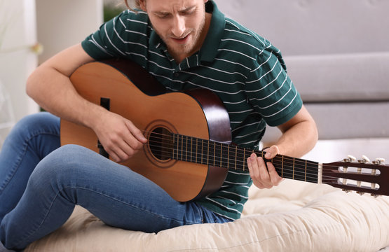 Young man playing acoustic guitar at home