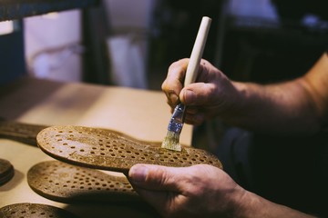 Hands making shoes. Making shoes manual. Shoemaker sitting in workshop making shoes. Footwear manufacture. Shoes factory.