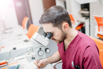 male doctor examines a sample with a microscope at a medical research center.