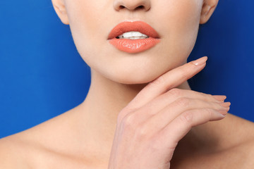 Fototapeta na wymiar Young woman wearing beautiful lipstick on color background, closeup
