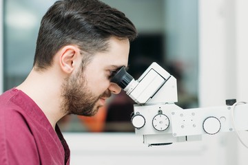 Fototapeta premium male doctor examines a sample with a microscope at a medical research center.