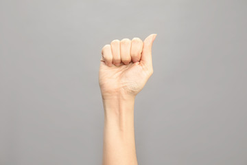 Woman showing A letter on grey background, closeup. Sign language