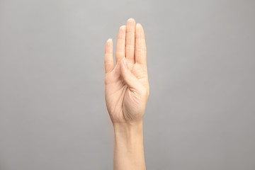 Woman showing B letter on grey background, closeup. Sign language