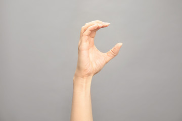 Woman showing C letter on grey background, closeup. Sign language