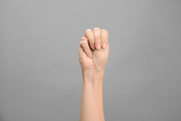 Woman showing M letter on grey background, closeup. Sign language
