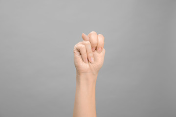 Woman showing N letter on grey background, closeup. Sign language