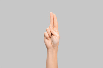 Woman showing U letter on grey background, closeup. Sign language