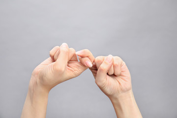 Woman showing word friend on grey background, closeup. Sign language