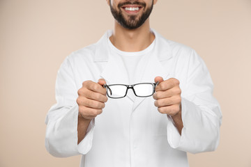 Male ophthalmologist with eyeglasses on light background, closeup