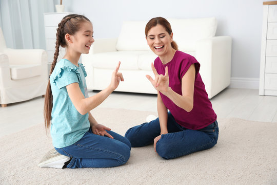 Hearing impaired mother and her child talking with help of sign language indoors