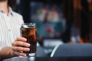 Woman with glass of refreshing cola at table indoors, closeup. Space for text
