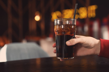 Man holding glass of refreshing cola at table indoors, closeup. Space for text