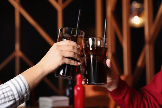 Young couple with glasses of refreshing cola indoors, closeup