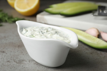 Ceramic dish of Tzatziki cucumber sauce with ingredients on table