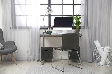 Stylish workplace with computer near window at home office. Space for text